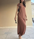 Woman wearing a brown outfit standing against a beige wall.
