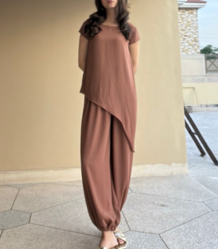 Woman wearing a brown outfit standing in front of a beige wall.