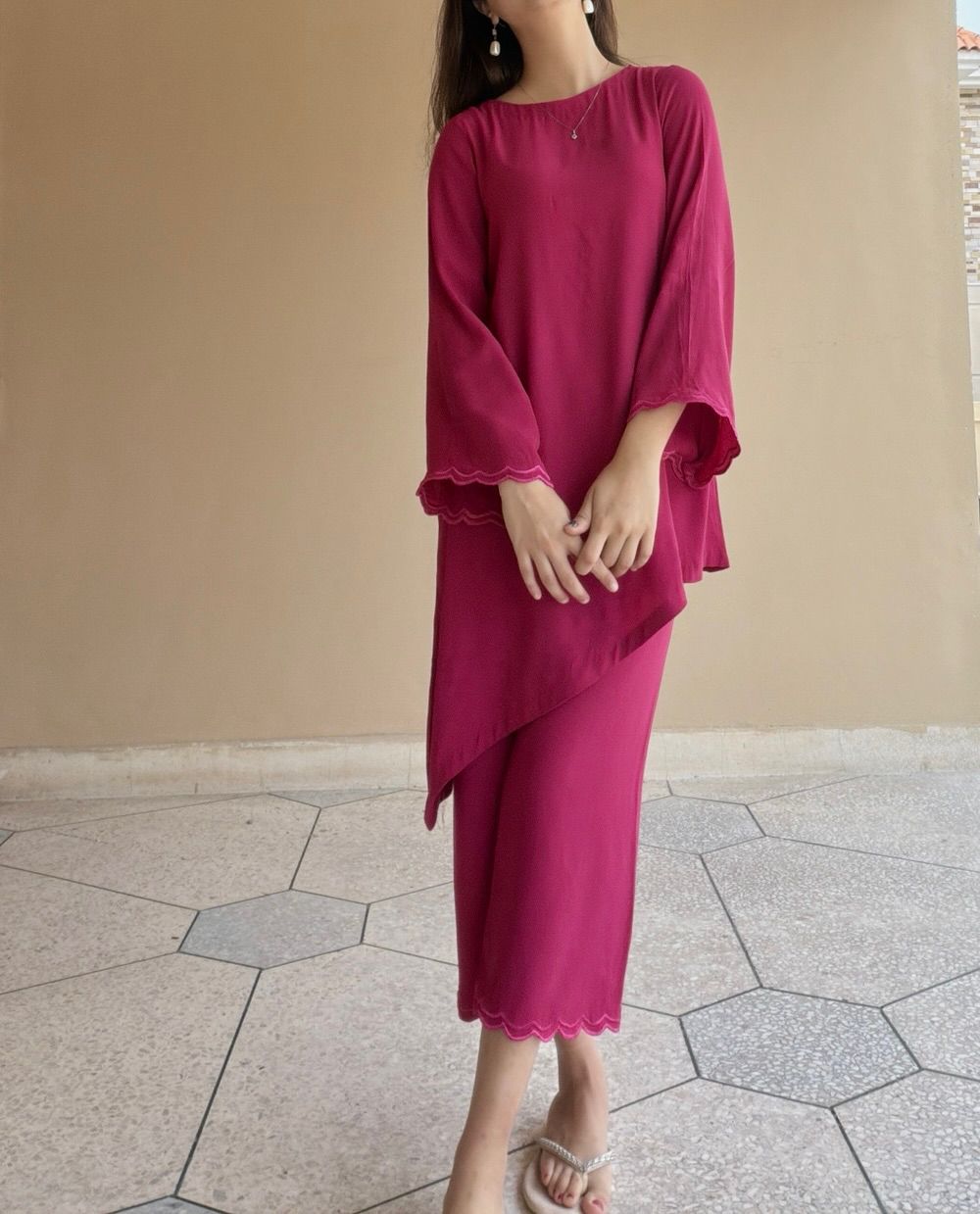 Woman wearing a magenta dress standing on a tiled floor with a beige wall in the background