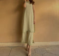 Woman wearing a light green dress standing against a beige wall.