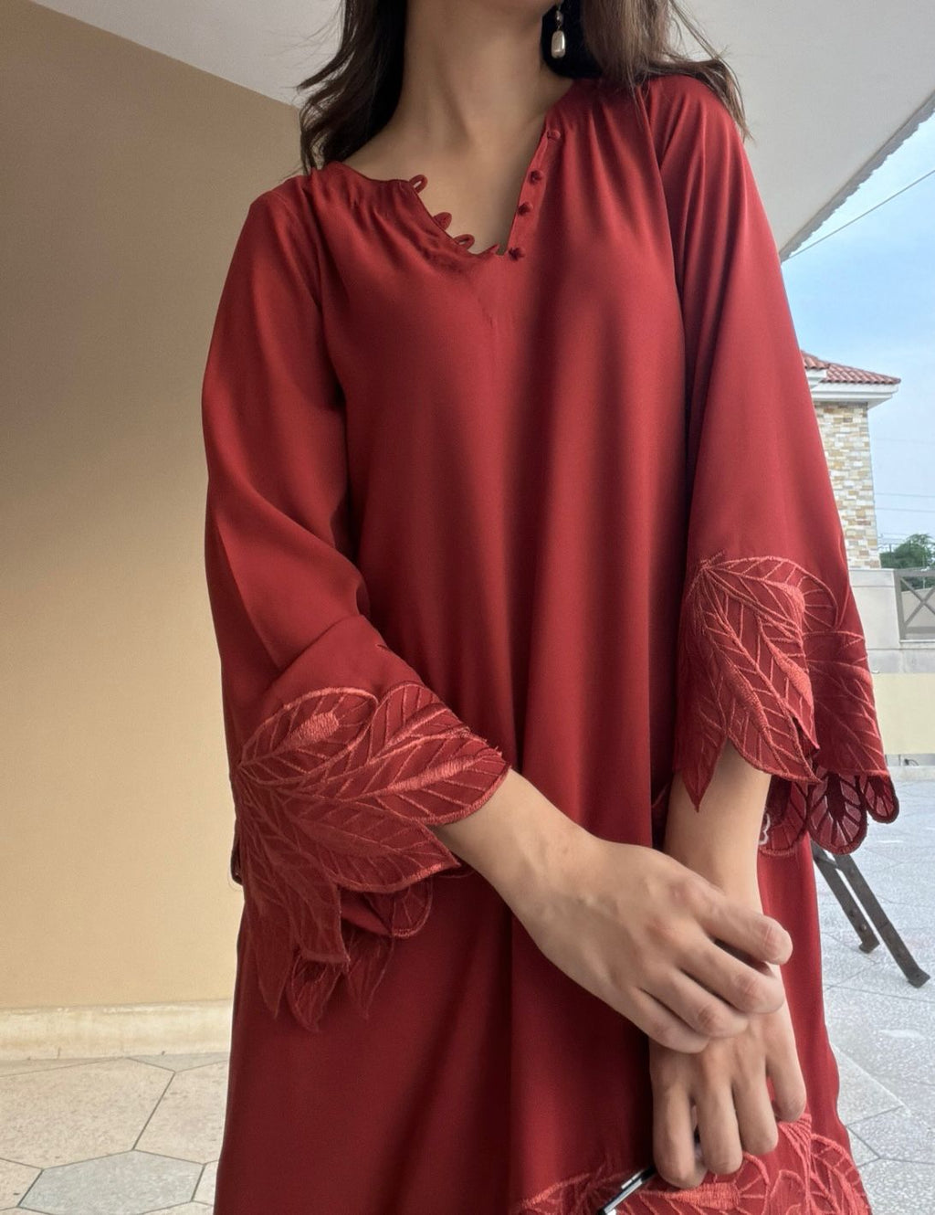 Maroon dress with intricate detailing on sleeves and neckline worn by a person.