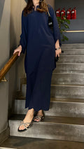 Person in a navy blue outfit standing on a staircase with fire extinguishers in the background.