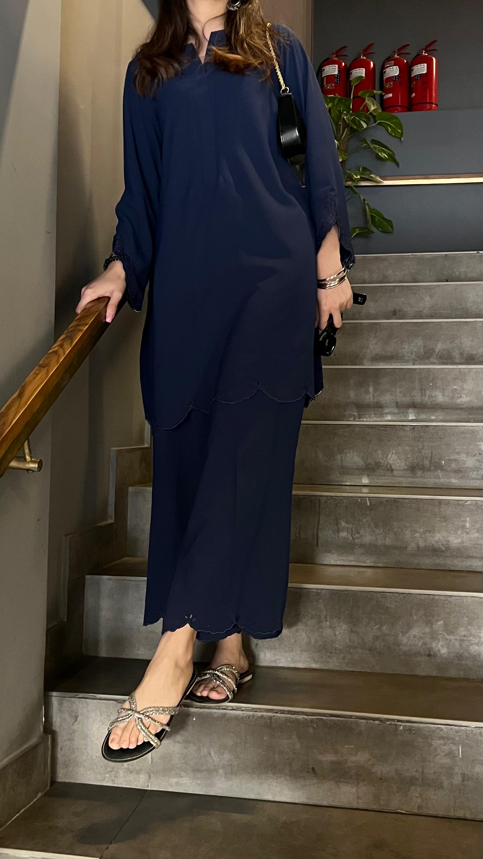 Person in a navy blue outfit standing on a staircase with fire extinguishers in the background.