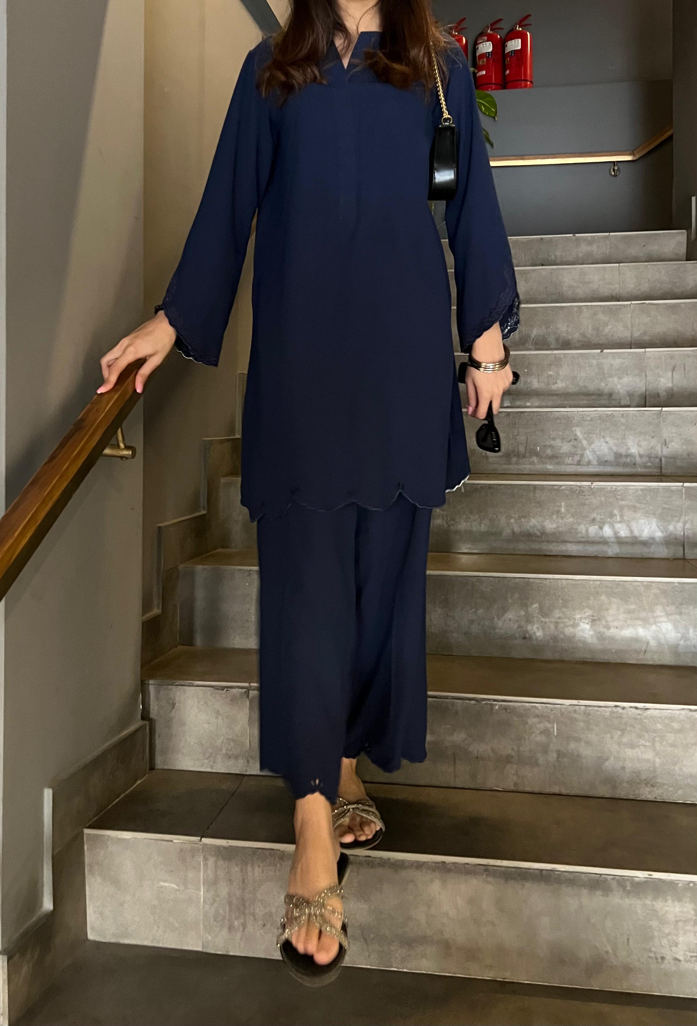 Person in a navy blue outfit walking up a staircase.